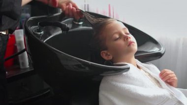 Kuaförde saçlarını yıkayan rahat bir kız. İsimsiz profesyonel stilist müşteri için saç stili yaratıyor. Stilist berber dükkanında çocukların saçlarıyla ilgilenir.