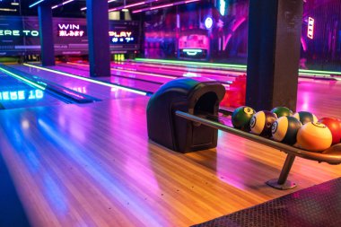 Bowling salonunda ahşap şeritli çeşitli bowling topları düzenlendi. Alışveriş merkezinde hiç insan olmadan aydınlatılmış oyun odası.