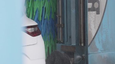 Otomatik işlemin bir parçası olarak, su jetleri ve fırça temizleme araçları ile, gün içinde otomatik oto yıkamada yıkanan beyaz araba