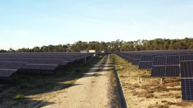 İnsansız hava aracı kırsaldaki bir güneş enerjisi santrali üzerinde alçaktan uçuyor, yenilenebilir enerji, sürdürülebilirlik ve yeşil teknolojiyi temiz enerjinin geleceği için anahtar olarak vurguluyor.