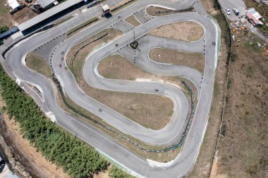 Uzaktan kumandalı hava aracı go-kartı yakalıyor. Üst hava perspektifinden dolambaçlı yarış pistlerinde ilerliyorlar. Kırsalda gündüz vakti yarışlara uzak bir bakış açısı 