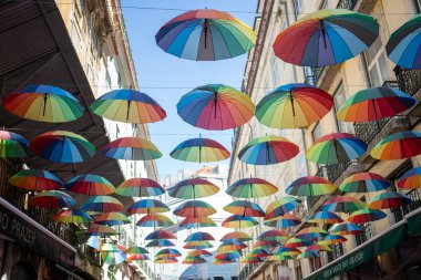 Onur yürüyüşü sırasında şehirde asılı duran gökkuşağı şemsiyelerinden. Gündüz vakti binaların arasında çok renkli nesneler süslenir. 