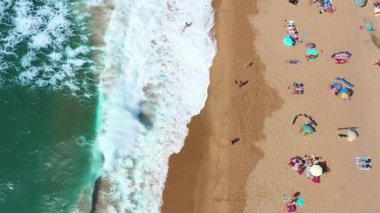 Portekiz 'in Sintra kentindeki ünlü sahil şeridine deniz dalgaları vuran Magoito sahilindeki turist ve şemsiyelerin insansız hava aracı görüntüsü