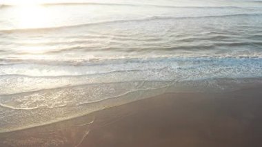 Deniz dalgalarının sahile ulaşması inanılmaz bir manzara. Güneş ışığı suya yansıyor. Havadan çekilen sakin ve ışıl ışıl kıyı manzarası yaratıyor.