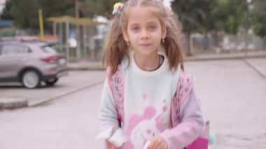 Sırt çantalı mutlu bir kız çocuğunun portresi. Gün boyunca sokakta yürüyor. Neşeli ve canlı bir şekilde yürümekten zevk alıyor.