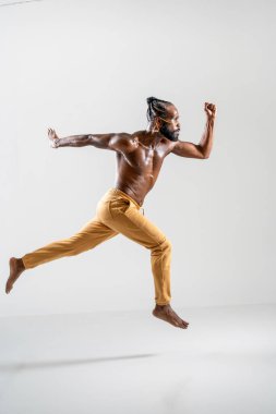 Gri arka planda zıplayan kararsız eşcinsel model. Stüdyoda havadaki güçlü genç adamın tüm vücudunu görebiliyoruz. 