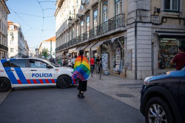 Şehir caddesinde yürürken arkasında gökkuşağı bayrağı olan bir kadın. Homoseksüel kadın LGBTQ haklarını kutluyor. 