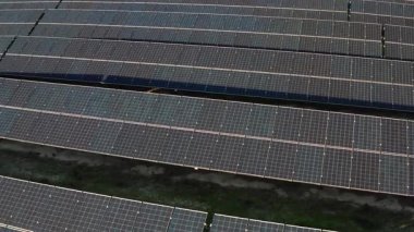Gündüz tarımsal alandaki güneş panellerinin yüksek açılı drone görüntüsü sürdürülebilir güç için yenilenebilir enerji jeneratörleriyle donatılmış geniş bir araziyi gösteriyor.