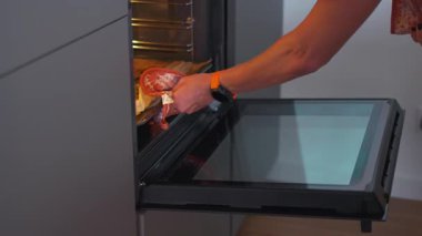 Kimliği belirsiz bir kadın somon dolu tepsiyi fırına koyuyor ve evde sıcak bir mutfakta ızgara yapıyor. Sahne, ev yapımı yemek hazırlama anını yakalıyor.