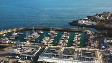 Portekiz 'in Cascais marinasında demirlemiş yelkenlileri çeken hava aracı görüntüleri güneşli bir günde limandaki tekneleri gösteriyor.