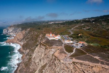 Cabo da Roca Deniz Feneri ve anıtının insansız hava aracı görüntüleri, Portekiz 'deki bu popüler tarihi yeri ziyaret eden uçurumlar, okyanus manzaraları ve turistler sergileniyor.