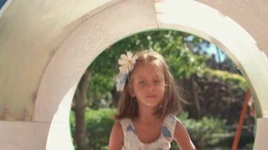 Çocuk parkında borularda sürünen çocuk, güneşli bir günde oyun bahçesinde tünelin içinde gezen sevimli küçük kız, açık havada eğlenceli aktiviteleri keşfediyor ve eğleniyor.