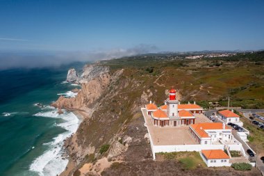 Uçsuz bucaksız okyanus ve bulutlarla çevrili Cabo da Roca Deniz fenerinin çarpıcı insansız hava aracı görüntüsü Portekiz kıyı şeridinin doğal güzelliğini gözler önüne seriyor.