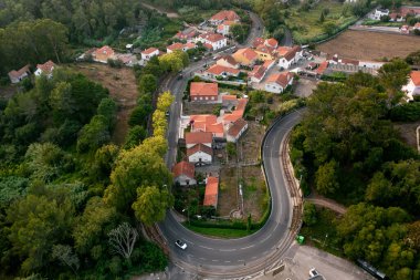 Portekiz 'in Sintra banliyösünden dolambaçlı yol manzarası. Yeşilliklerin ortasında arabalar yerleşim bölgesinin kıvrımlarını ve virajlarını dolaşır.