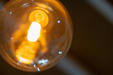 Aşağıdan çekilen yakılmış ampulün yakını. Parıltı, ampul detaylarıyla sıcak ve davetkar bir ortam yaratıyor.