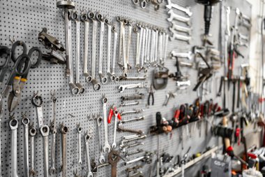 Çeşitli anahtarlar ve el aletleri mekanik tamirat ve bakım için düzenli depolama çözümleri sağlayan atölyedeki tahta üzerinde sistematik olarak düzenlenmiştir