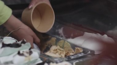 Gevşemiş, neşeli anlarda, renkli tatlarla çevrili dondurmaları dondurma standında, kağıt bardağa doldurmak.