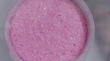 Hazırlık aşamasında doku ve tutarlılığı gösteren küçük kabarcıklarla dolu pembe silikon karışımının üst görünümü