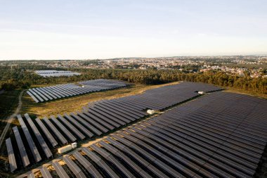 Güneş panelleri sıralı güneş çiftliği ağaçlarla çevrili geniş bir alanı kaplar. Paralel çizgilerde, güneş ışığını maksimuma çıkaran paneller düzenlenmiştir. Yerleşim alanı arka planda görülebilir