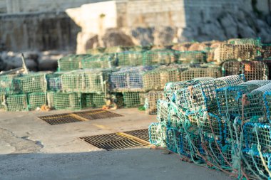Yengeç kapanları rıhtım boyunca düzgünce istiflenmiştir, yaklaşan balık mevsimi için hazırlanmışlardır. Tuzaklar iyi korunuyor ve bu kıyı bölgesinde sürdürülebilir balıkçılık uygulamaları için kullanılmayı bekliyor..