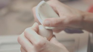 Sanatçı, daha fazla detay vermeden ve adımları tamamlamadan önce kusurları ortadan kaldırmak için yumuşak kumaşlı, pürüzsüz yüzeyi olan silikon bebek başını dikkatlice kumlar.