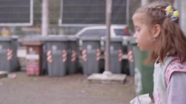 Sırt çantası ve beslenme çantasıyla sokakta yürüyen liseli kız, okula giderken konuşan tatlı bir kızın yan görüntüsü.