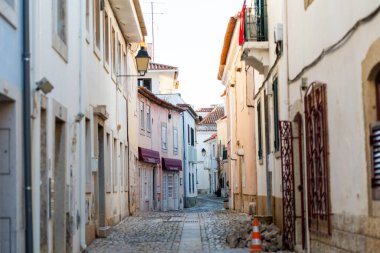 Cascais 'deki huzurlu kaldırım taşı caddesinde renkli yüzlü geleneksel mimari sergileniyor. Dükkanlar ve evler ziyaretçiler için tuhaf bir atmosfer yaratırken güneş sıcacık bir parıltı yayıyor..