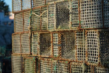 Güneş arka planda batarken, kıyı bölgesinde birkaç yengeç kapanı bir araya toplanır ve sıcak bir parıltı yayar. Tuzaklar, onları korumak için bir kafes tasarımı ve ipler içeriyor..