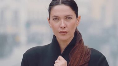 Şehir caddesinde ciddi bir yüzü olan, siyah ceketli, önüne bakan, insanlarla ve binalarla geçmişi bulanık, kentsel yaşam tarzı konseptiyle kendinden emin genç bir kadın.