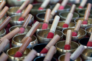 Bir çan satıcısı canlı bir pazarda bir dizi el yapımı şarkı kasesi sunar. Her kaseye bir tahta tokmak eşlik eder ve geleneksel müzik aletlerinin rengarenk bir görüntüsünü oluşturur..