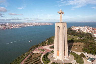 Kral İsa 'nın anıtının hava aracı görüntüsü. Gökyüzünün altındaki Almada ve Tagus Nehrinin manzarasına bakan heykel