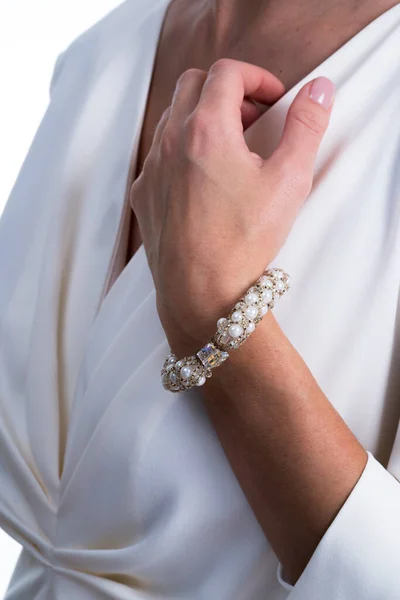 Woman\'s hand with jewelry, white dress.