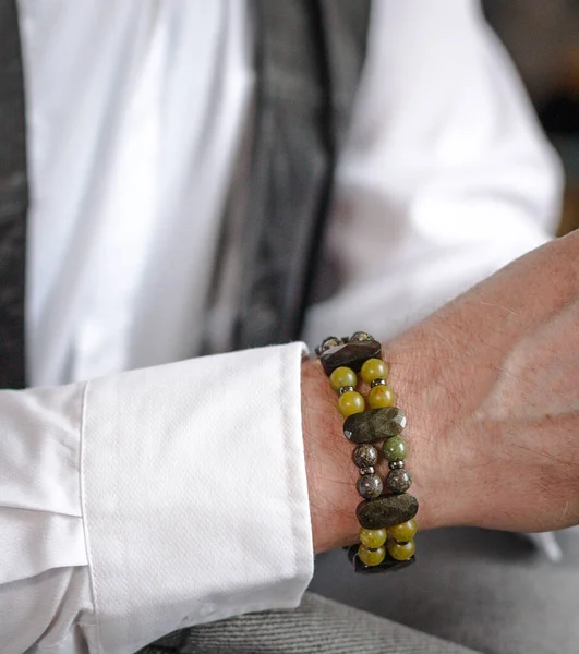 A man's bracelet made of natural stones can be seen on the hand, close-up