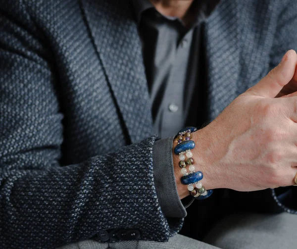 A man\'s bracelet made of natural stones can be seen on the hand, close-up