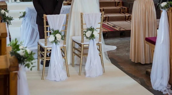 Decoration of chairs during the wedding process in the church