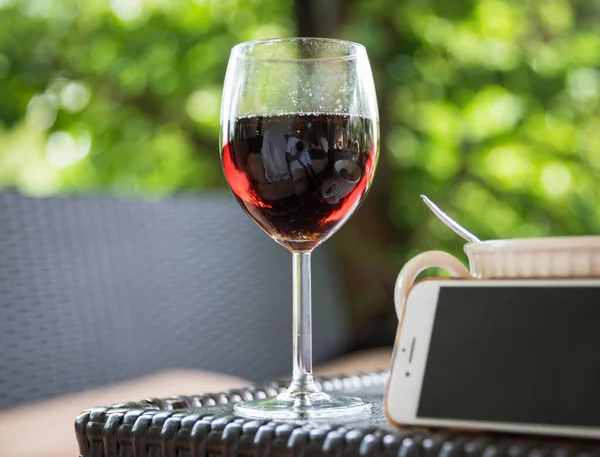 Bahçe masasının köşesinde şarap kadehi, seçilmiş odaklanma, arkaplan bulanıklaştırılmış.