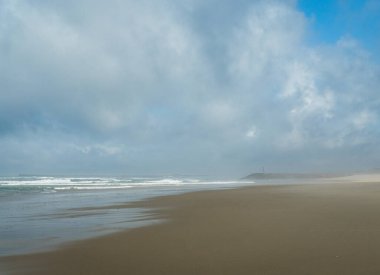 Atlantik Okyanusu 'nun dalgaları kumlu sahili yıkıyor, ufuk görünür durumda, gün bulutlu..