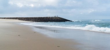 Atlantik Okyanusu 'nun kumlu sahili kayalık iskelesi, okyanusta küçük dalgalar, gökyüzü bulutlu, bulutlu..