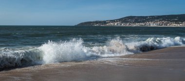 Atlantik Okyanusu 'nun dalgaları kumlu sahili yıkıyor, ufuk görünür durumda, gün bulutlu..