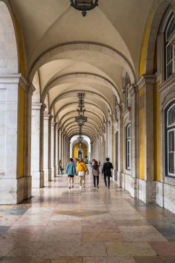 Lizbon, Portekiz - 10.04.2019: Sütunlu kemerli koridor; insanlar yürüyor; Praca do Comercio Meydanı; güzel mimari.