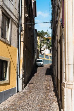 Coimbra / Portekiz - 10 / 02 / 2019: Coimbra 'da taşlarla döşenmiş dar bir sokak, sokağın sonunda büyük bir ağaç büyüyor.