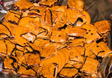 Orta tabakada reçelli Noel çöreği, kahverengi, çikolata jöleli, gümüş tepside kare parçalara bölünmüş..