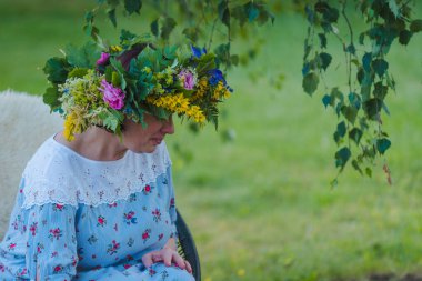 Yaz gündönümü çelengi, el yapımı, doğada oturan kadın..