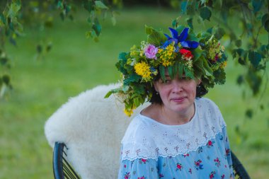 Yaz gündönümü çelengi, el yapımı, doğada oturan kadın..