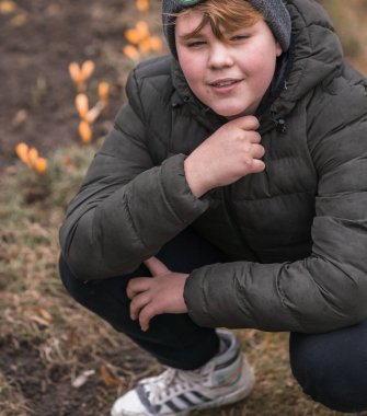 Kırsal kesimde genç bir Avrupalı çocuğun portresi, bir bahar günü, keyifli, kahverengi ceketli ve gri şapkalı..