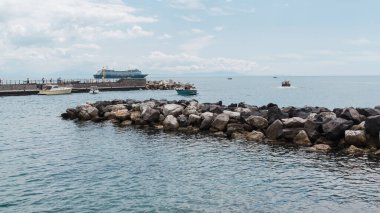 Amalfi, İtalya - 27 Nisan 2025: Amalfi kasaba iskelesinde Akdeniz, iskele ve koruyucu kaya yığını. Amalfi Sahili, İtalya.