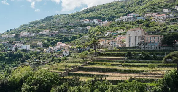 Amalfi, İtalya - 27 Nisan 2025: Yamaçta Amalfi kıyısında bahçeleri ve manikürlü bitkileri olan evler. Dar yılan yolları.