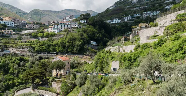 Amalfi, İtalya - 27 Nisan 2025: Yamaçta Amalfi kıyısında bahçeleri ve manikürlü bitkileri olan evler. Dar yılan yolları.
