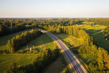 Letonya 'nın yeşil doğasına kuş bakışı bakış açısı, çayırlar, ağaçlar, ormanlar, tarlalar, Jelgava bölgesindeki evler. Güneşli hava, akşam.