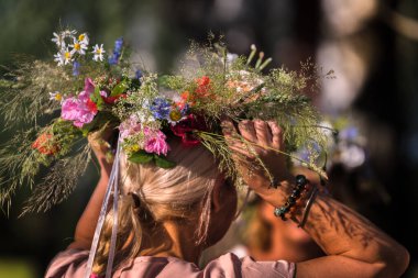 Yaz gündönümü çelengi ve bahçe çiçekleri sarı saçlı ve saçı örgülü bir kız için, el yapımı, odak noktasında bireysel parçalar, yaz günü